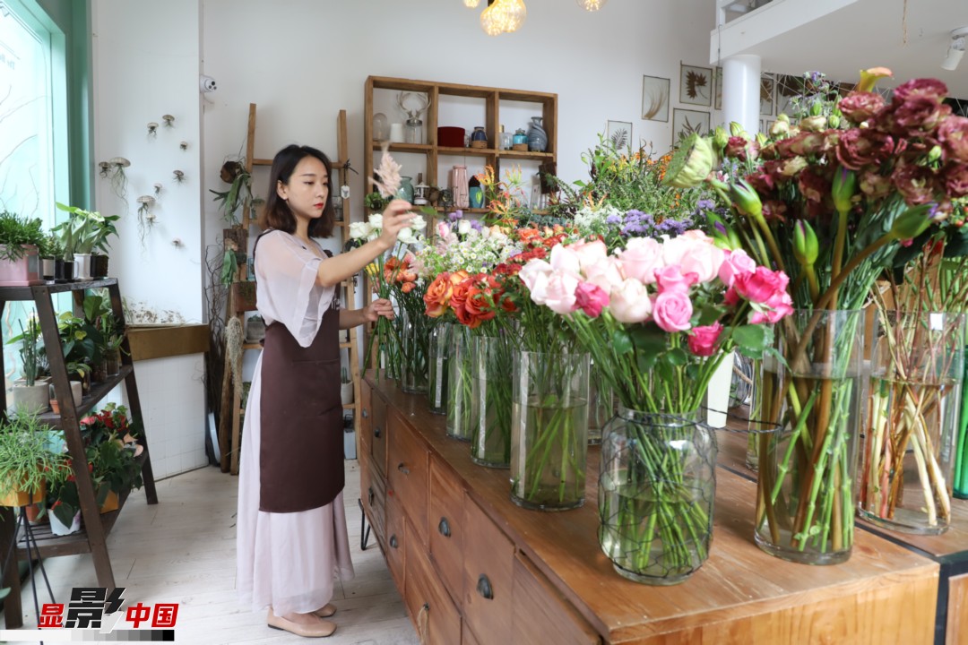 王黎媛是一名河南姑娘，在昆明念完大學(xué)后，就再也舍不下春城的藍(lán)天陽光、青山碧水，更舍不下這里的四時繁花，于是就干脆留了下來，成了一名媒體人。2017年的時候又毅然辭去工作，創(chuàng)業(yè)開起了花店，成了都市里的一名“花房姑娘”。圖為王黎媛在自己的花店中整理鮮花。新華網(wǎng) 周亞平/攝 念新洪/文